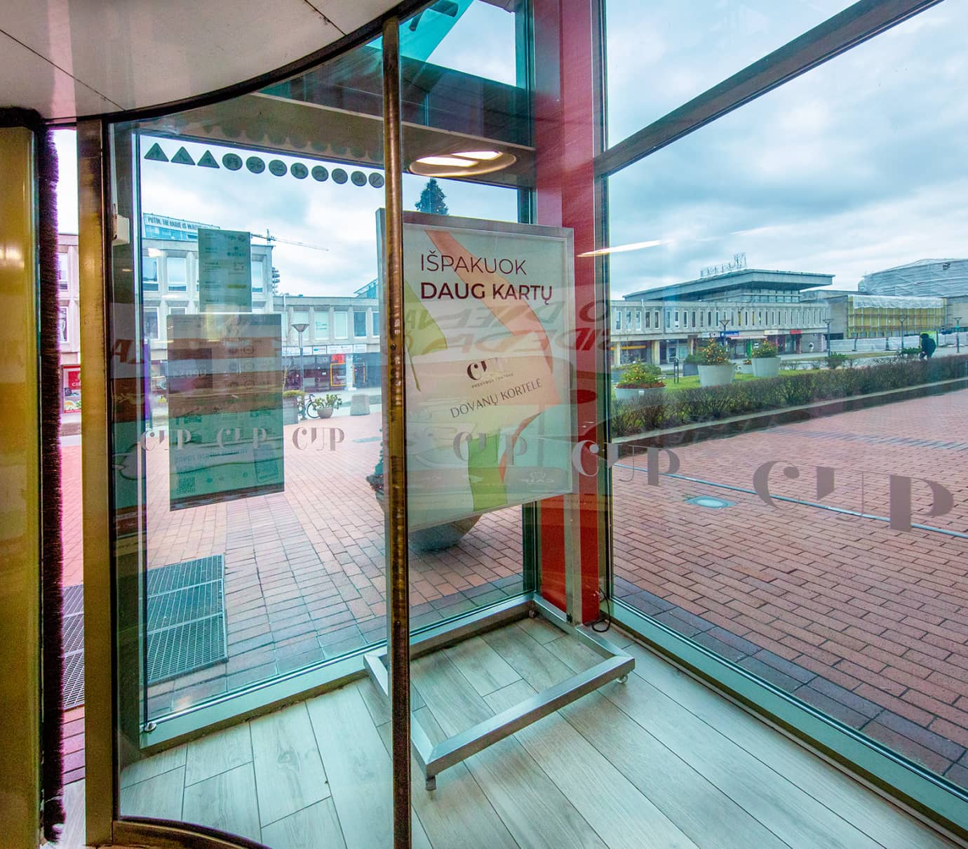 Plakatas prie besisukančių durų