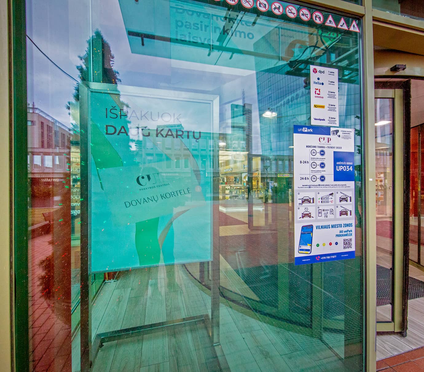 Plakatas prie besisukančių durų